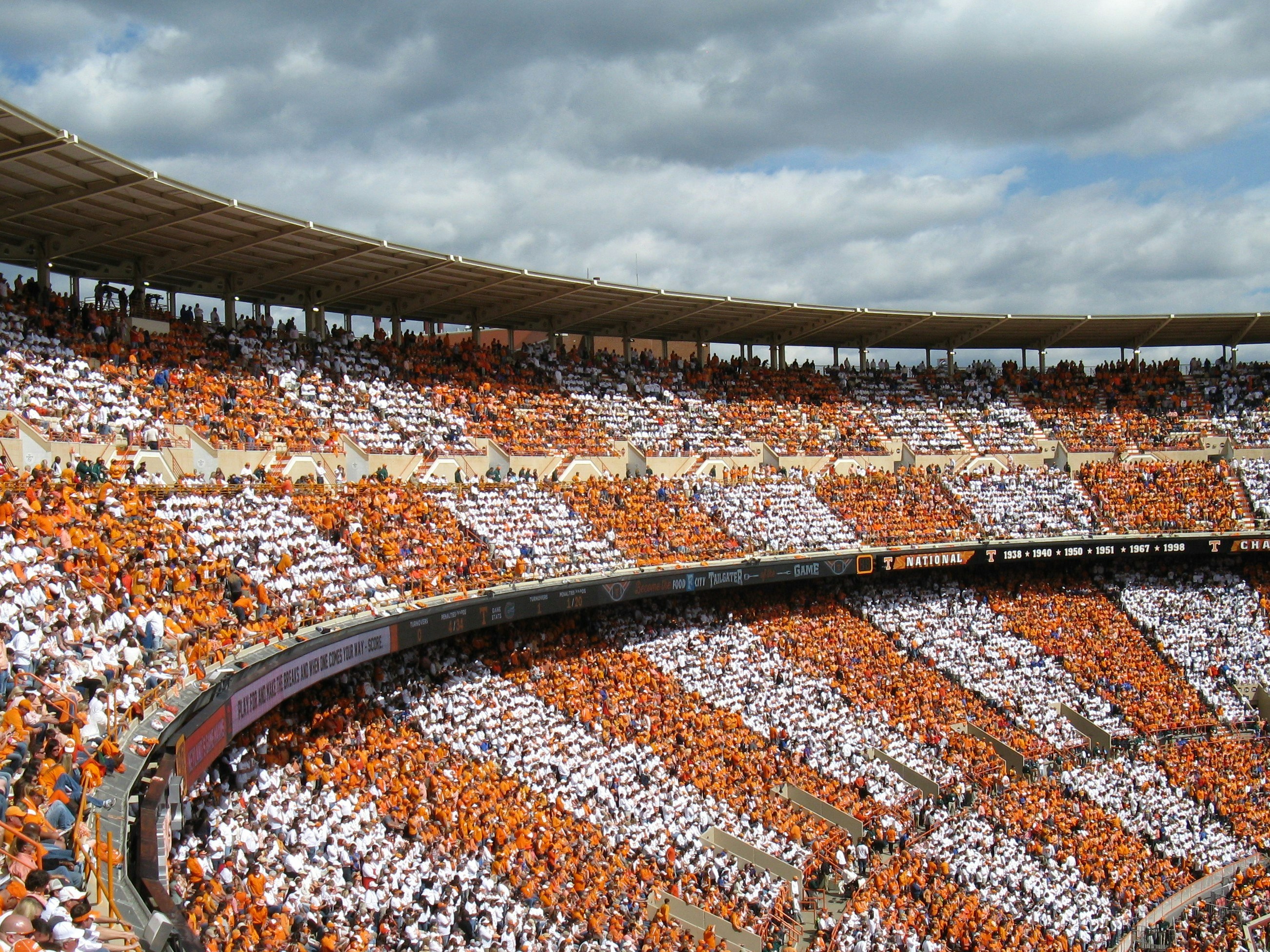 Fans fill a football stadium during a daytime game.