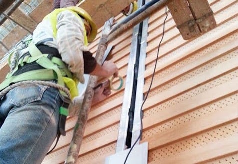 A contractor works on a wall expansion joint in a commercial building.